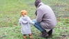 Ein Vater spielt mit seinem Sohn in einem Park.