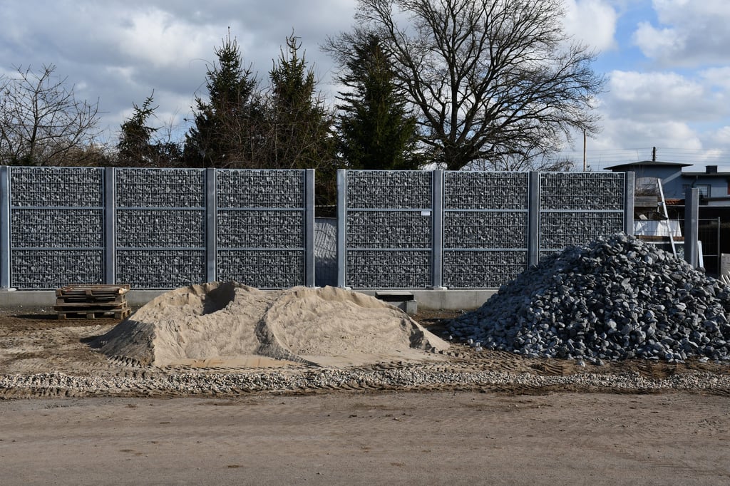 Ein mit Steinen gefüllter Sichtschutz entsteht derzeit an der neuen Straßenbahnstrecke in Magdeburg. Für zwei Grundstücke soll es eine Hecke geben.