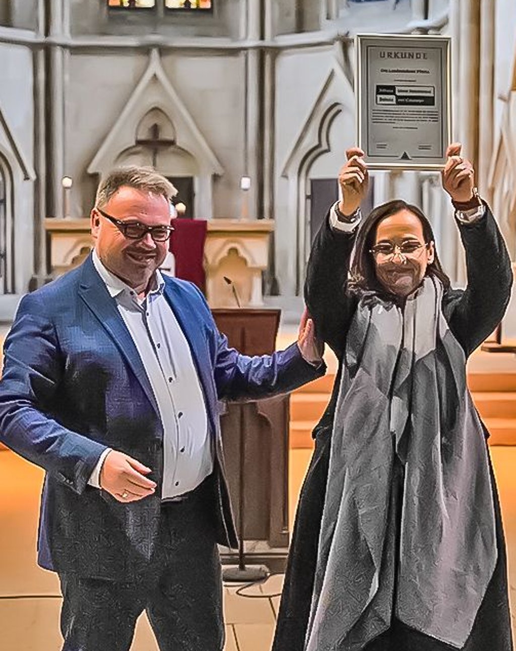 Maik Reichel übergibt die Anerkennungsurkunde an Rektorin Kathrin Volkmann.