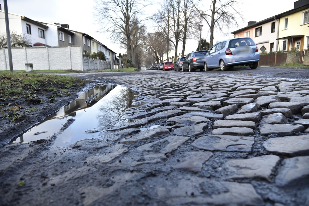 Die gepflasterte Fahrbahn weist Unebenheiten und Schadstellen auf.