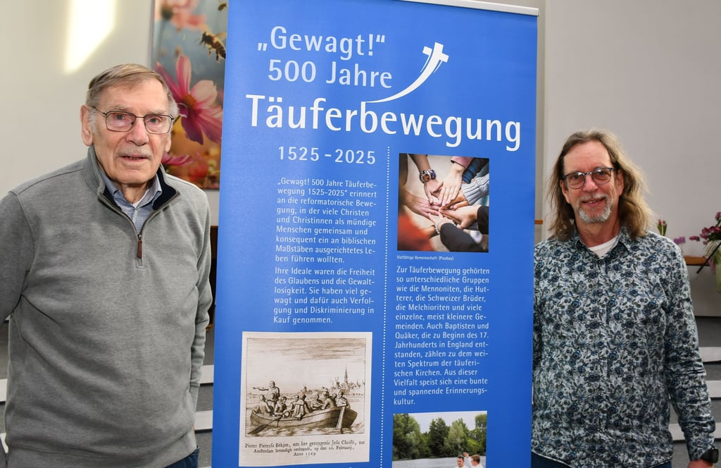 Die Magdeburger Erich Geldbach (links) und Bernd Willerding mit einem Banner der Ausstellung zur Geschichte der Täuferbewegung.