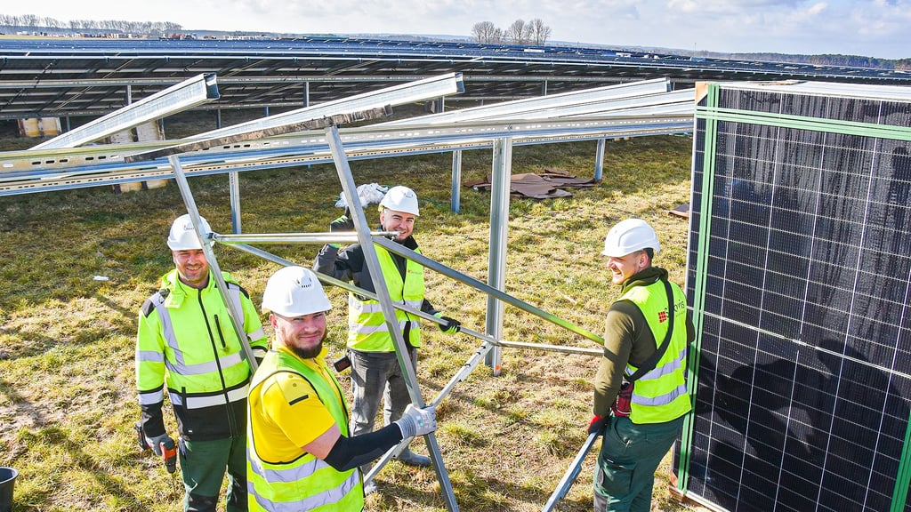 Arbeiter stellen im Solarpark „Klüden Nord“ Tische auf, auf denen die Photovoltaikmodule montiert werden. Diese Gestelle bieten eine stabile und flexible Basis für eine optimale Ausrichtung der Module zur Sonne.
