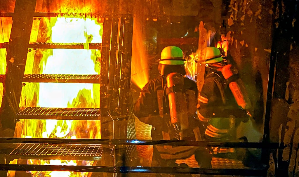 Wenn es bei der Ausbildung im engen Brandcontainer wie hier in Fischbeck unter der Treppe brennt, ist der Rückzugsweg abgeschnitten. Deshalb muss dieses Feuer immer zuerst bekämpft werden. Das Foto wurde durch eine Scheibe aufgenommen, hinter dieser hat der Bediener stets alles im Blick.