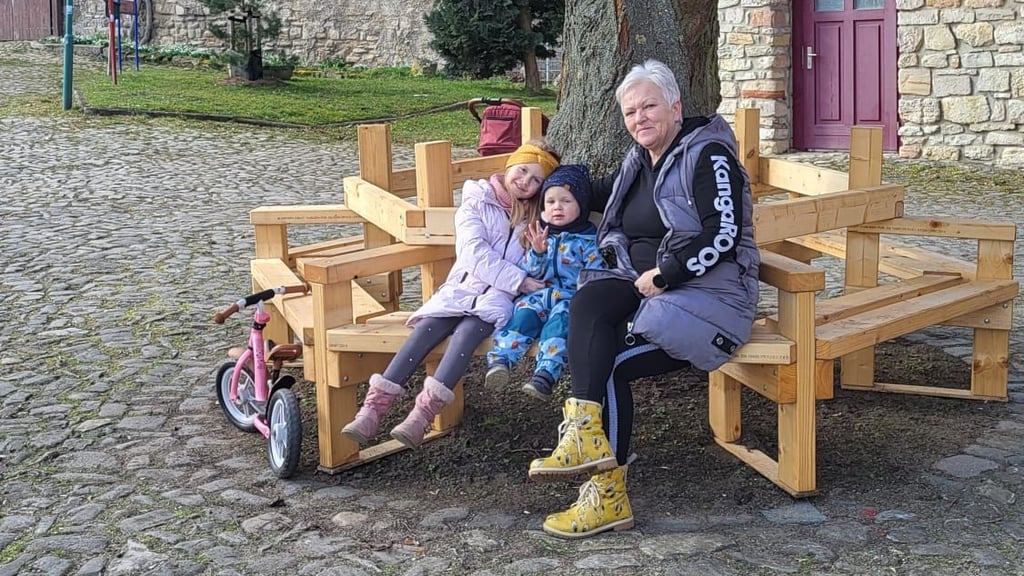 Conny Müller mit ihren Enkeln Juna und Liam, die nach dem Besuch des Spielplatzes an der Burg Schlanstedt im Landkreis Harz ein Päuschen auf der Bank machen.