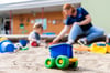 Ein Kind spielt im Sandkasten einer Kita mit einer Erzieherin. In Magdeburg sind viele Kita-Plätze frei.