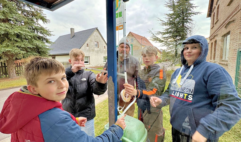 Unter Anleitung von Jan Blaue bringen diese Jungs reflektierende Punkte in Abständen von neun Zentimetern auf der Scheibe der Bushaltestelle an.