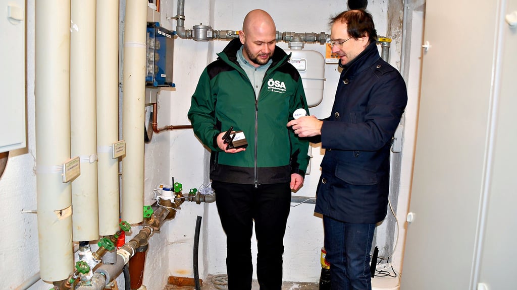 Christian Endter von Prothinx (rechts) zeigt Martin Schmidt von der ÖSA im Keller des Havelberger Rathauses das Gerät, das auf die Wasseruhr kommt. Unregelmäßigkeiten könnten auf einen Wasserschaden hindeuten.