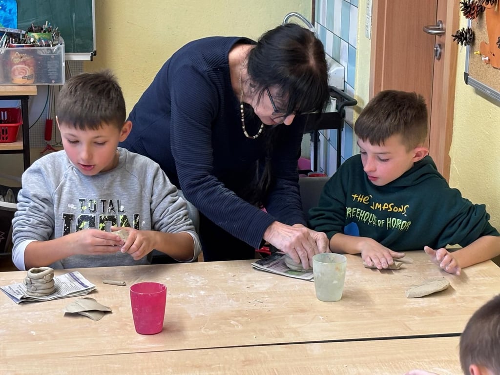 Die beiden Grundschüler kreieren mit Hilfe einer Keramikkünstlerin eigene Gefäße aus Ton.