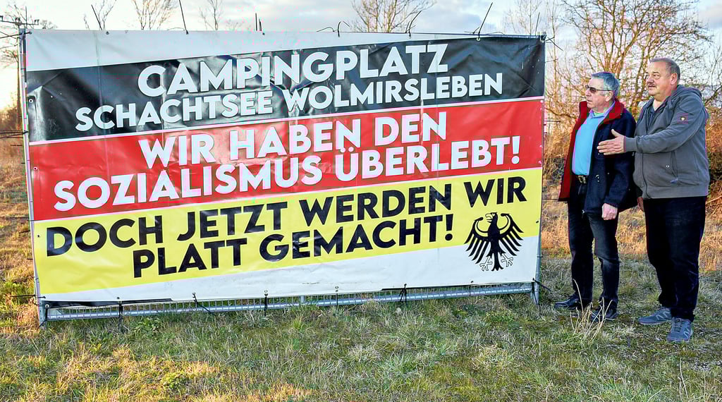 Als Zeichen ihres Protestes gegen die vom Salzlandkreis verfügte Schließung des Campingplatzes zum Monatsende haben die Camper ein Protestbanner an der Landesstraße nach Egeln aufgestellt. Manfred Fürst und Rüdiger Koppe (r.) schauen sich den Text an.