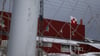 Eine grönländische Flagge weht in Ilulissat zwischen einem zugeschneiten Fußballplatz und einer Sporthalle.