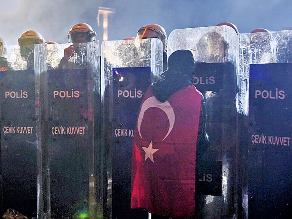 Ein Mann steht während einer Demonstration in Istanbul vor Polizisten.