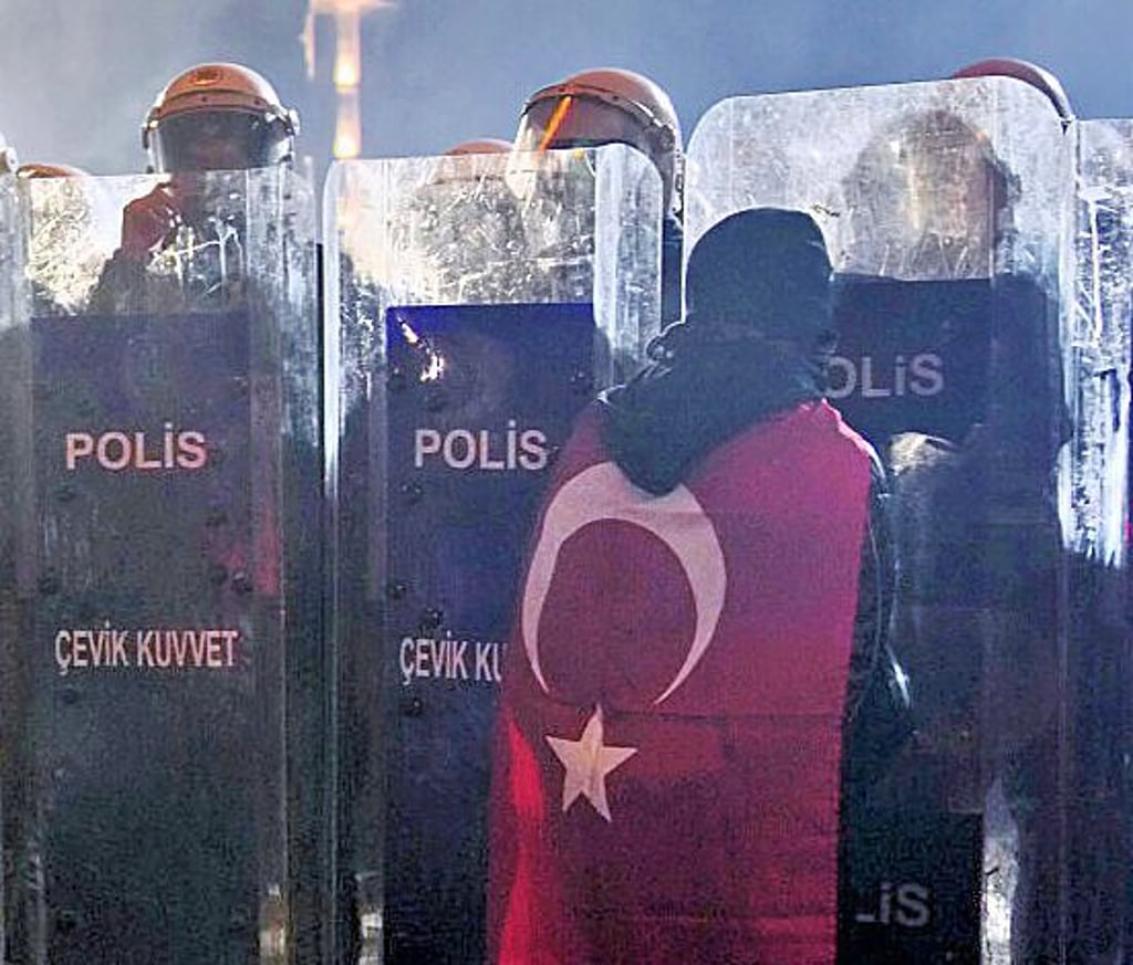 Ein Mann steht während einer Demonstration in Istanbul vor Polizisten.