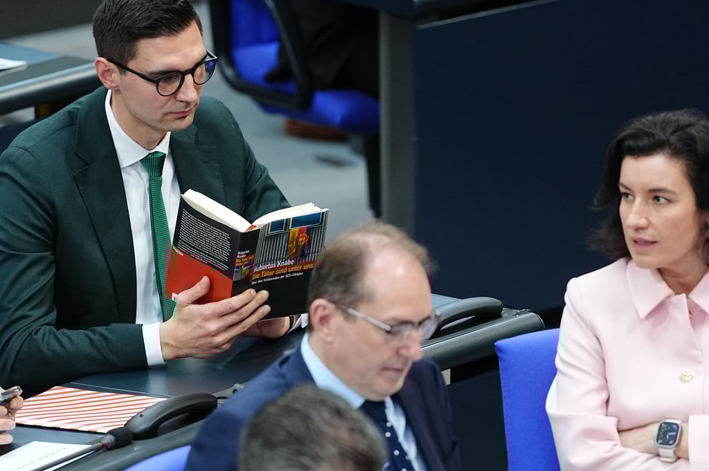 Der Abgeordnete Sepp Müller (CDU) hält das Buch "Die Täter sind unter uns" während der Rede von Alterspräsident Gregor Gysi (Die Linke) in den Händen.