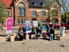 Akteurinnen und Akteure, darunter Gabriele Herrmann, Elrid Pasbrig und Karina Cleve (v.l.) sowie Maria Pfannkuchen (1.v.r.), während der Hocker-Aktion am 18. April 2024 auf dem Genthiner Marktplatz.