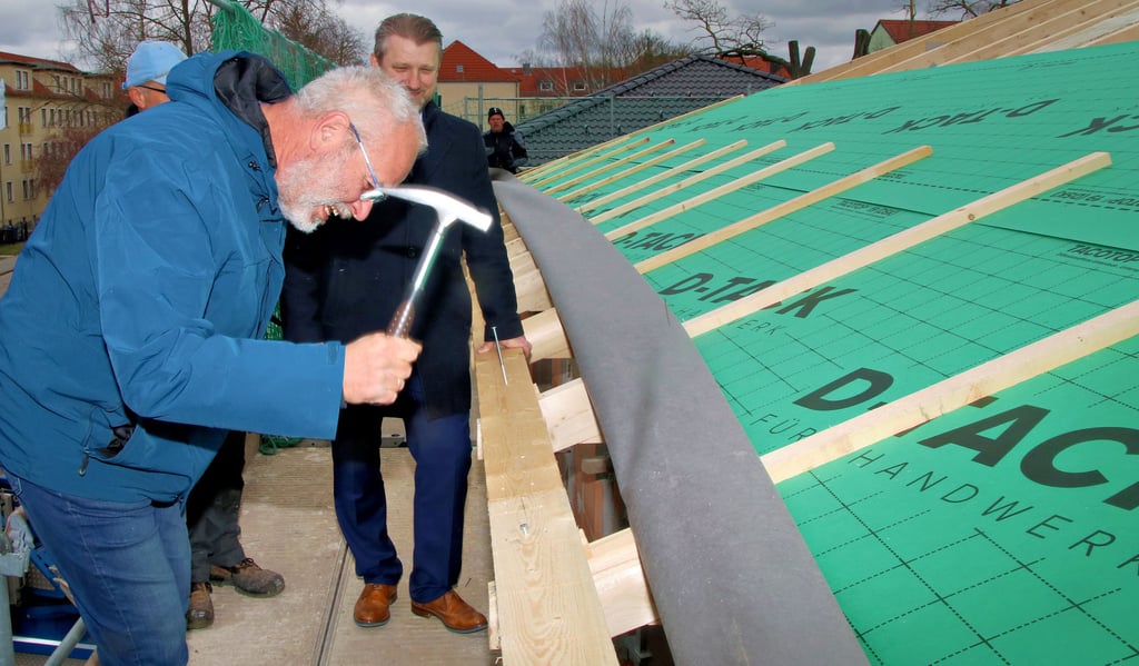 Ralf Dahlke, der Leiter der Technik bei der Calbenser Wohnungsbaugesellschaft schlägt hier einen der letzten Nägel in den Dachstuhl. Daneben steht Bürgermeister Sven Hause.