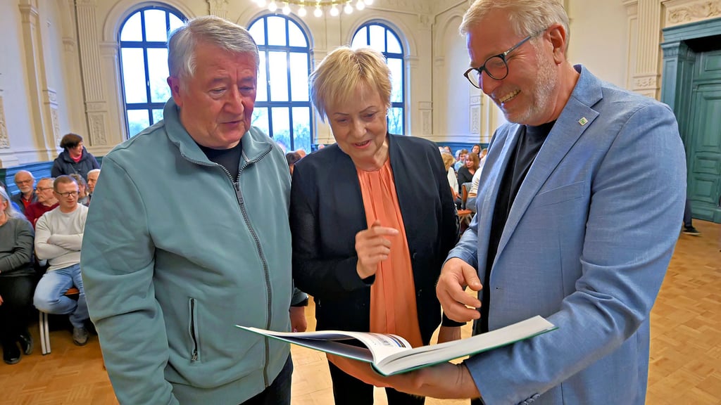 Die Autoren Frank und Andrea Janzen werfen gemeinsam mit Schulleiter Axel Wieczorek (von links) einen Blick in die Chronik.