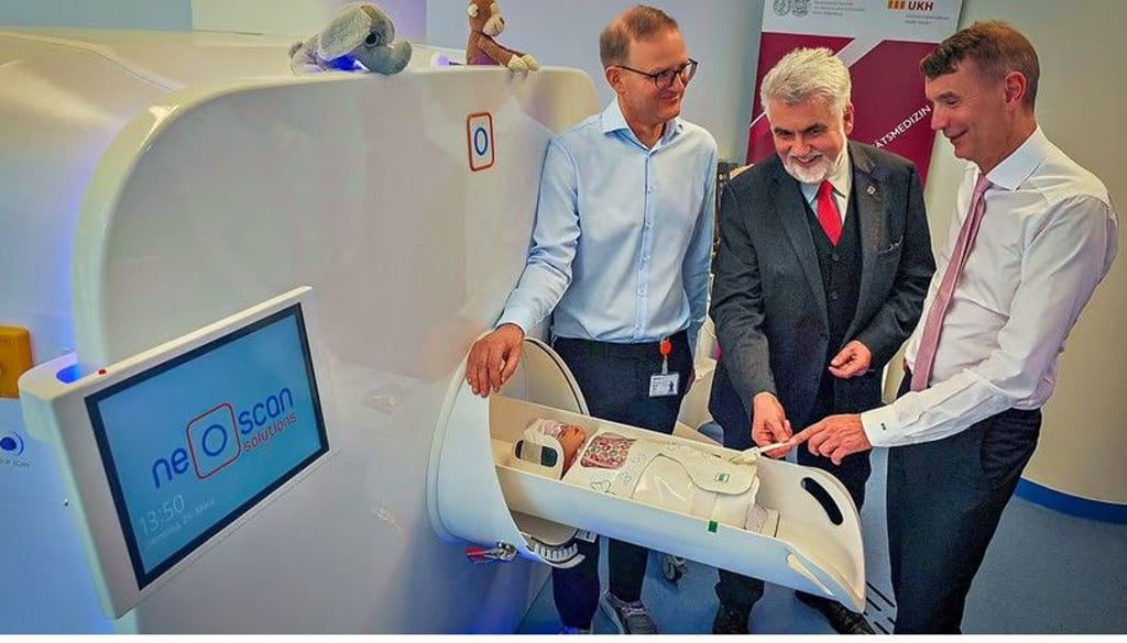 Die Mediziner Roland Haase (li.) und Walter Wohlgemuth (re.) zeigen Wissenschaftsminister Armin Willingmann, wie das MRT für Babys funktioniert.