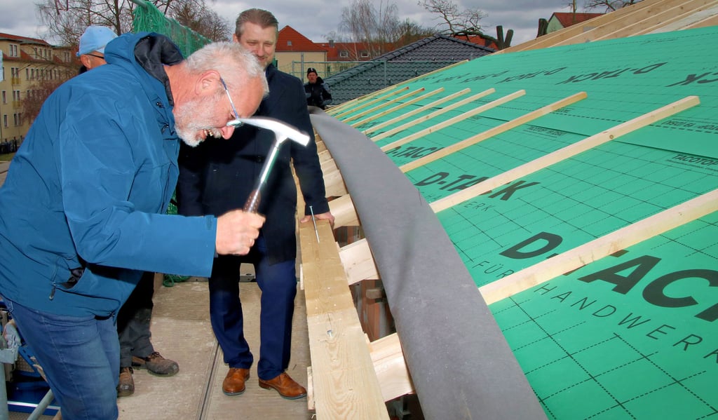 Ralf Dahlke, der Leiter der Technik bei der Calbenser Wohnungsbaugesellschaft schlägt hier einen der letzten Nägel in den Dachstuhl. Daneben steht Bürgermeister Sven Hause.