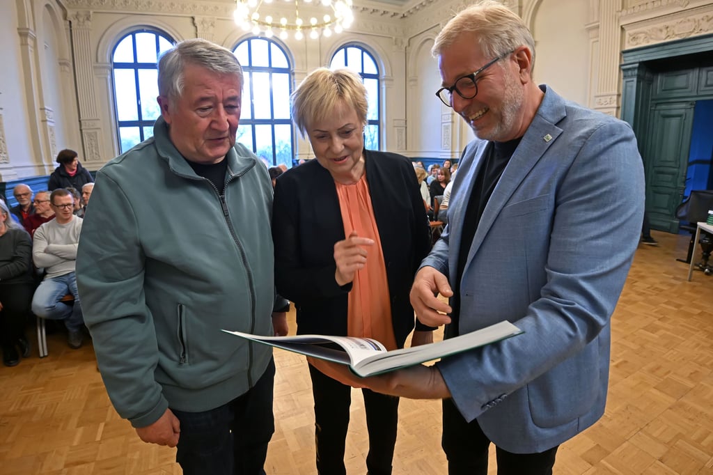Die Autoren Frank und Andrea Janzen werfen gemeinsam mit Schulleiter Axel Wieczorek (von links) einen Blick in die Chronik.