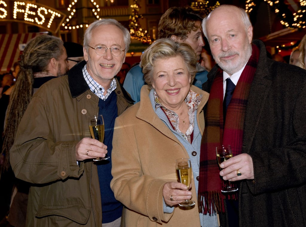 Die Schauspieler Joachim Hermann Luger (Hans Beimer, links) und die Schauspieler Marie-Luise Marjan (Mutter Beimer) und Bill Mockridge (Erich Schiller, rechts) posieren in der Außenkulisse mit Sektgläsern nach der Live-Ausstrahlung der 1559. Folge im Dezember 2015.