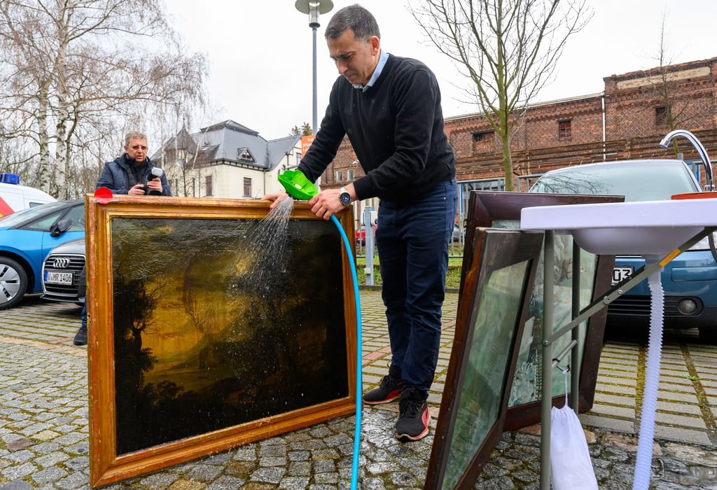 Basher Abd el Kader, Restaurator der Ratsschulbibliothek in Zwickau, spült bei einer Notfallübung ein Gemälde an einem mobilen Waschtisch.