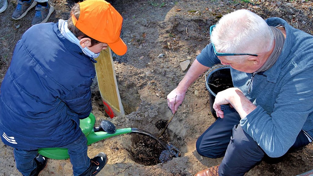Auch die jüngeren Kinder greifen zur vollen Gießkanne: Detlef Schulze hält dabei den noch zarten Setzling in der Hand.