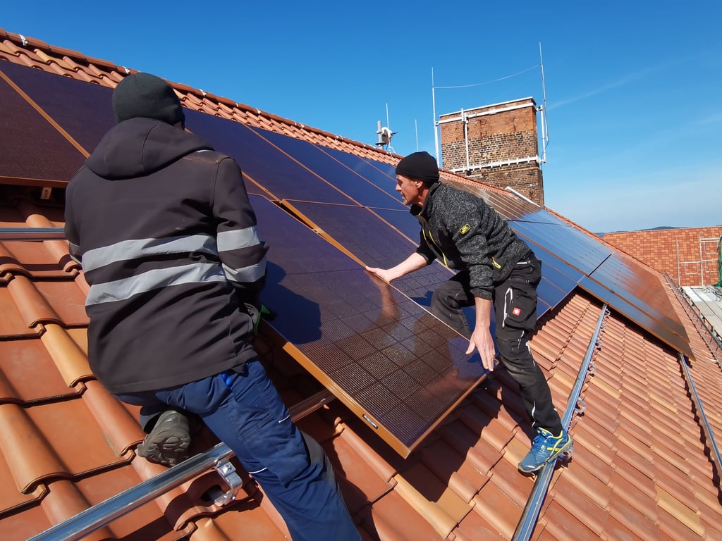 Mitarbeiter von SEM aus Gernrode installieren rote Photovoltaik-Module auf dem Dach von Haus II der Blankenburger Stadtverwaltung.