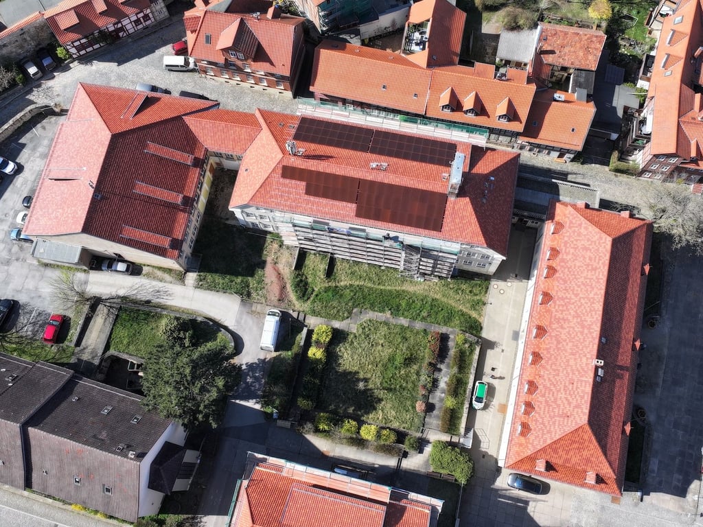 Drohnenaufnahme vom Haus II der Blankenburger Stadtverwaltung mit der roten PV-Anlage. In nächsten Schritten sollen weitere Dächer auf dem denkmalgeschützten Ensemble mit solchen PV-Modulen versehen werden.