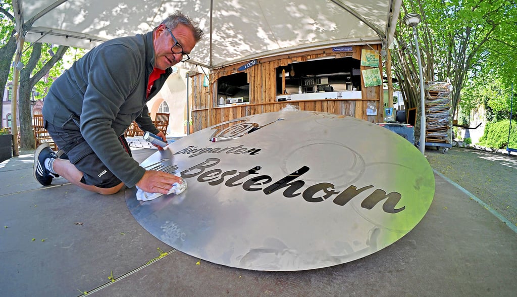 Denis Bromann putzt das Schild, bevor es an prominenter Stelle angebracht wird.