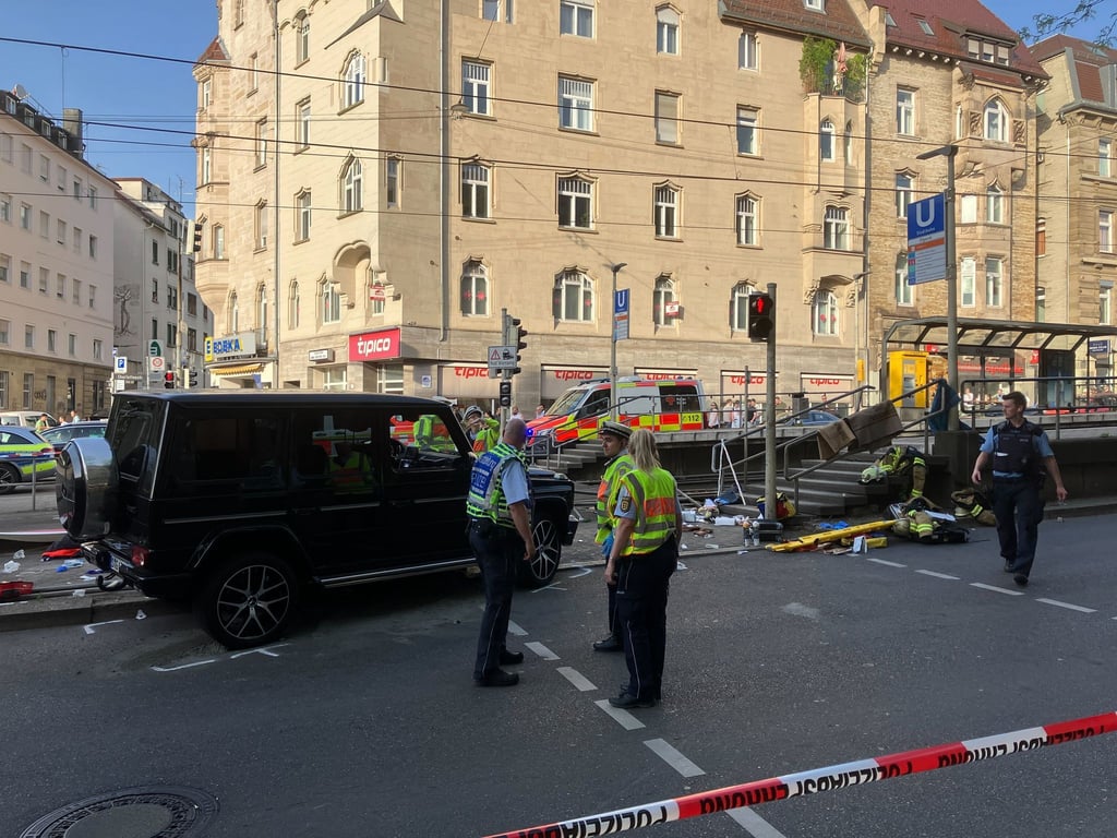 Am frühen Abend fährt ein Fahrzeug in eine Menschengruppe an einer Bahnhaltestelle.