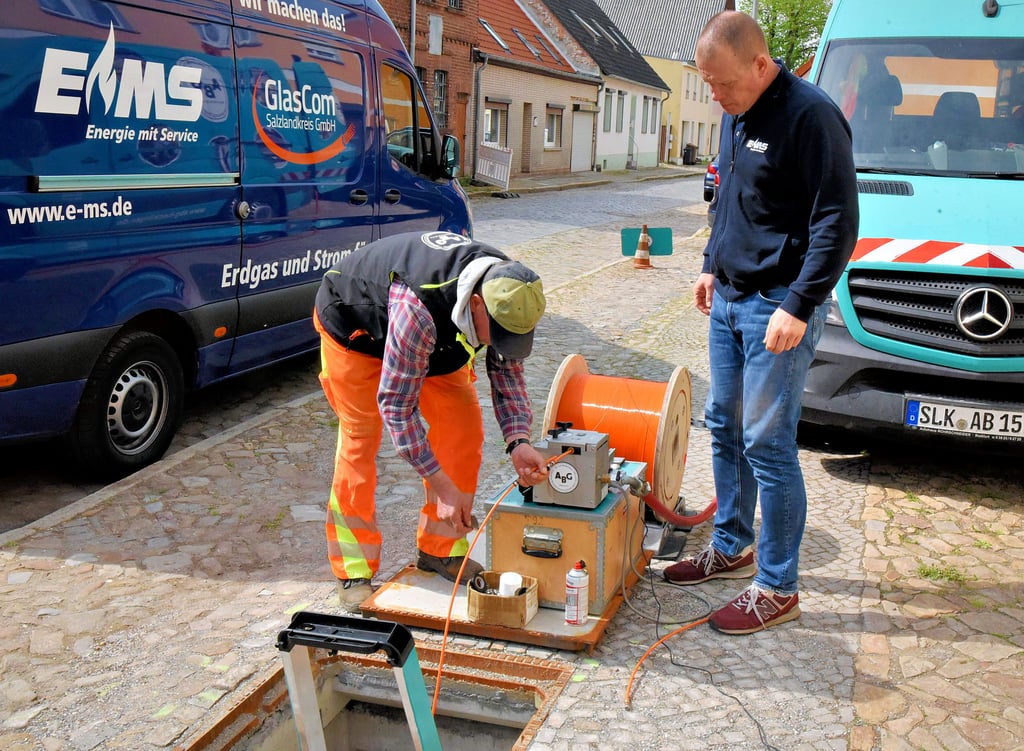Uwe Krieg (l.) und Marc Landgräbe, der als EMS-Netzmeister die Baustelle betreut, am Einblasautomat in der Schulzenstraße in Barby.