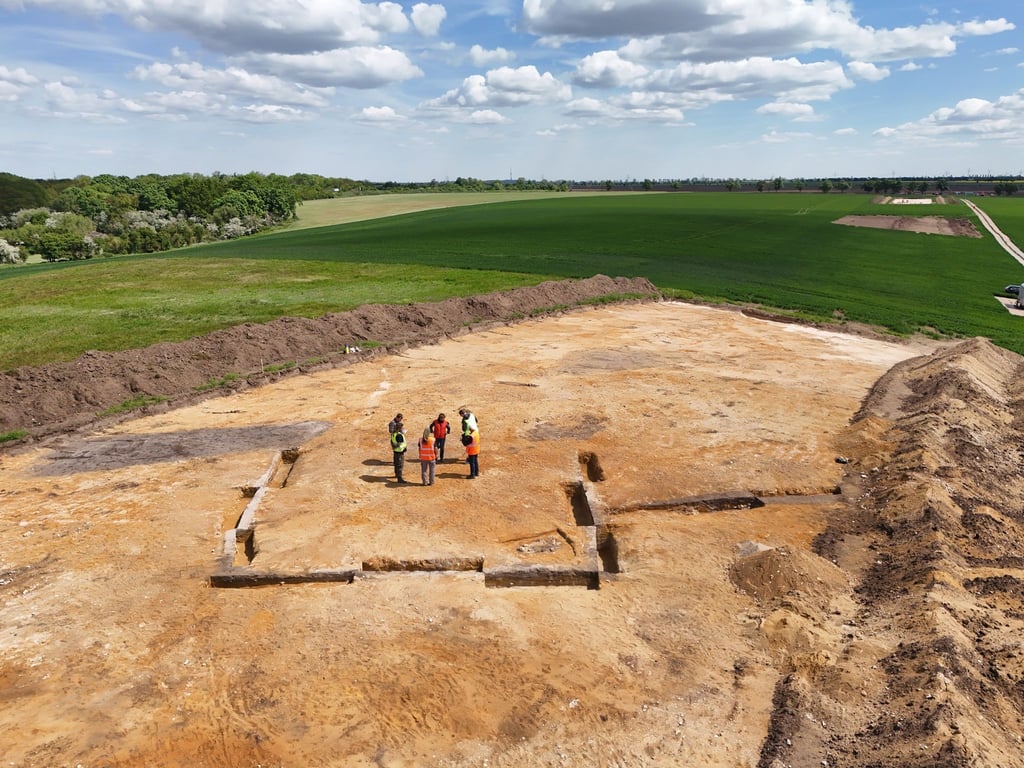 Archäologen stehen inmitten einer Trapezanlage. Dort stand einst eine Baalberger Trapezhütte, die auch überhügelt war.