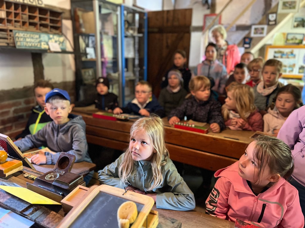 Gebannt lauschen die Grundschüler, auf historischen Schulbänken sitzend, den Ausführungen im Badersleber Heimatmuseum.