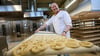 Backen ist Kunst: Brot-Sommelier Florian Lutz steht in seiner Backstube und schiebt ein Blech Brezeln in den Ofen.