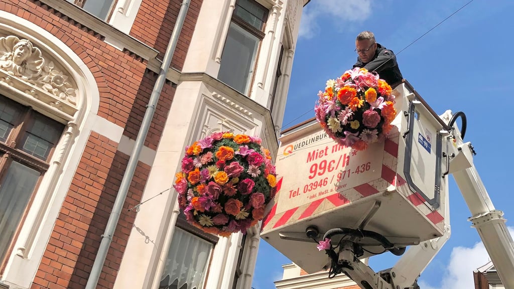 Nico Bier, Mitarbeiter der Stadtwerke Quedlinburg, bringt Blumenkugeln in der Steinbrücke an.
