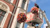 Nico Bier, Mitarbeiter der Stadtwerke Quedlinburg, bringt Blumenkugeln in der Steinbrücke an.