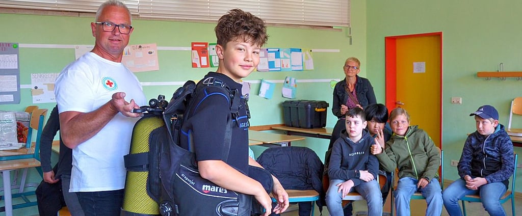Jörg Jehniche von der Wasserwacht Oschersleben erklärt den Schülern im Gymnasium Oschersleben die Funktionen einer Taucherausrüstung. Carlo darf sie anprobieren.
