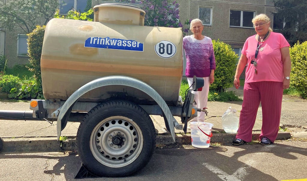 Petra Dobrowolski und Ilona Lemke holen Wasser aus dem Kanister vor ihrem Wohnhaus in der Friedhofstraße 26.