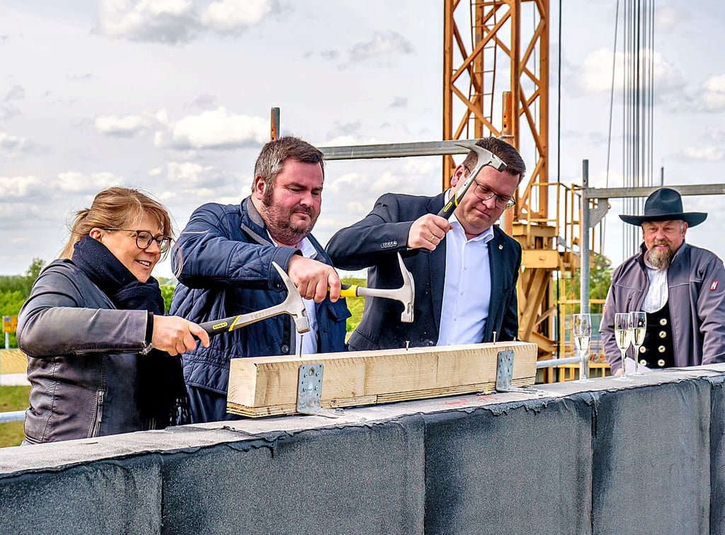 Und alle: Beim Einschlagen des symbolischen letzten Nagels zum Richtfest am Vormittag des 8. Mai ist Landrat Christian Tylsch nicht allein.
