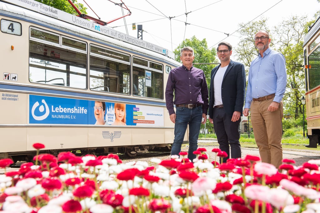 35 Jahre Naumburger Lebenshilfe: Hartmut Dorsch (v.l.), David Strauß und Marco Henschler freuen sich über die neue Werbung an der Straßenbahn samt dem neuen Slogan „Genau mein Ding“.