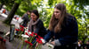 Menschen legen bei der Gedenkveranstaltung zu Çetin Merts Tod vor 50 Jahren Blumen vor die Gedenktafel.