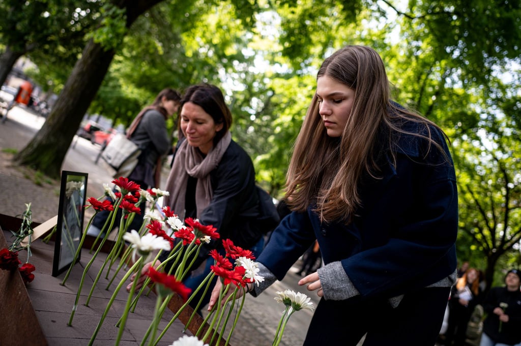 Menschen legen bei der Gedenkveranstaltung zu Çetin Merts Tod vor 50 Jahren Blumen vor die Gedenktafel.