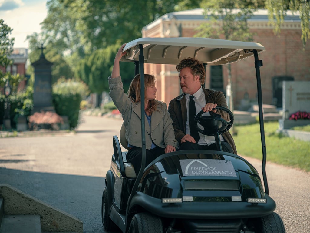 Ursula Fink (Julia Jentsch) und Heli Wondratschek (Nicholas Ofczarek) in einer Szene aus der ersten Staffel der Serie „Drunter und Drüber – Chaos auf dem Friedhof“ (Prime Video).
