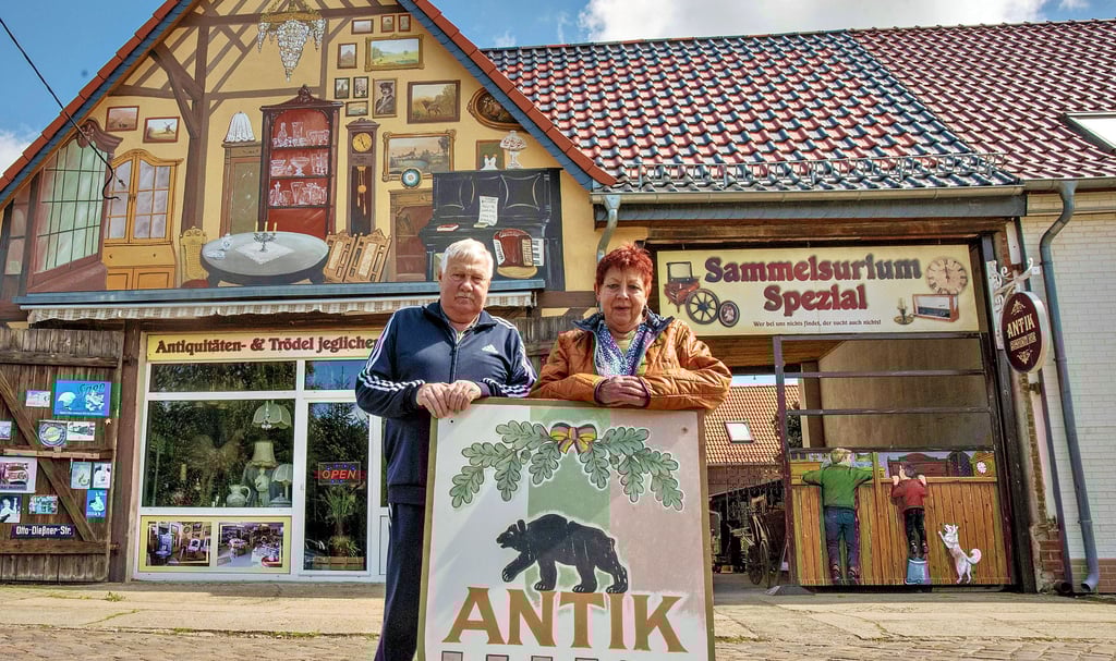 Rainer Büttner und seine Frau Viola betreiben seit zehn Jahren ihr „Sammelsurium“, einen Trödelladen in Mildensee. Die Malerei am Hausgiebel zeigt Interessenten den Weg. Gestaltet wurde sie vom Köthener Kunstmaler Steffen Rogge.