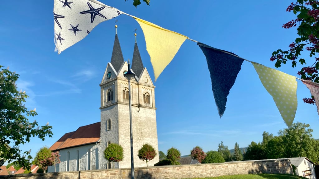 Eine bunte Wimpelkette zieht sich durch Minsleben zum 1.025-jährigen Jubiläum des Dorfes bei Wernigerode - auch an der Kirche St. Margareten entlang.