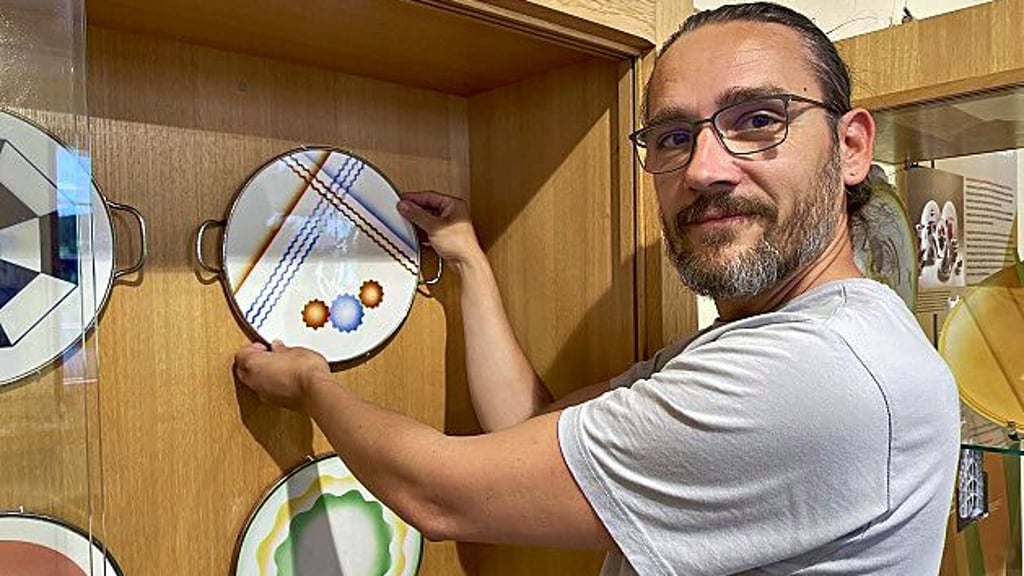 Museumsmitarbeiter Christian Waldenheim bereitet die Sondersausstellung mit kunstvoll gestalltetem Geschirr vor.