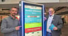 Harald Gläser und Hans-Jörg Bliesener (v.l.n.r.) präsentieren das neue Parksystem. Auf den Bildschirmen erscheint beim Einfahren das Kennzeichen.