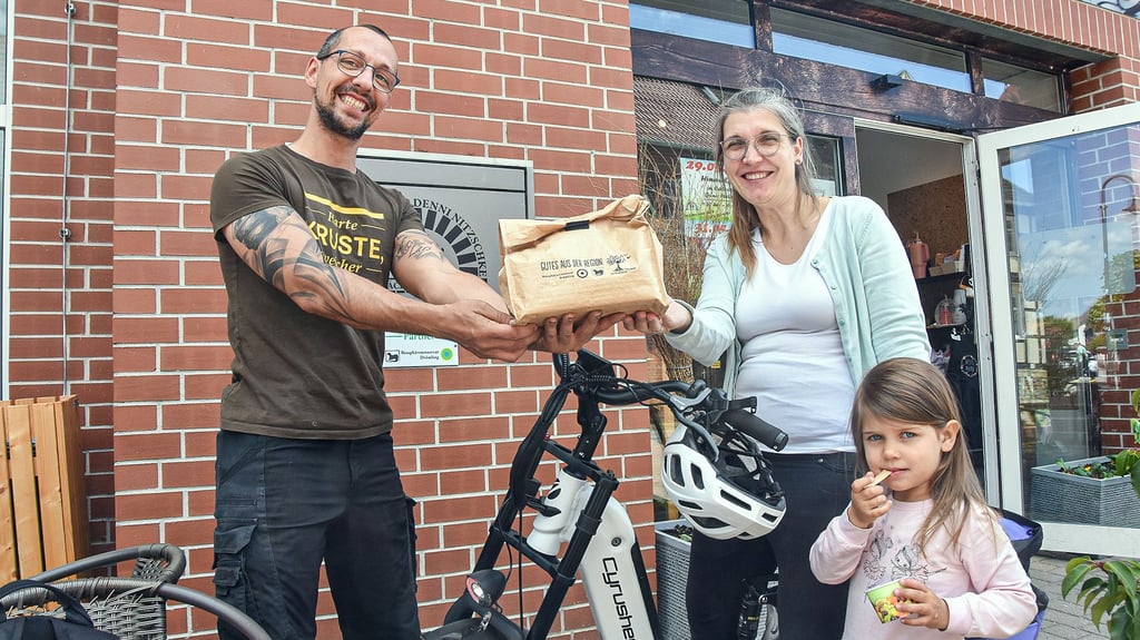 Bäckermeister Denni Nitzschke aus Calvörde überreicht an Madeleine Witzke und ihrer Tochter Charlotte einen Picknick-Beutel gefüllt mit regionalen Köstlichkeiten für eine Pause in der Natur.