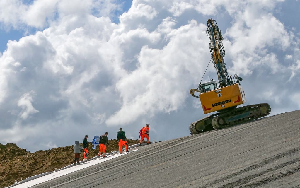 Arbeiter verlegen auf der Deponie 3.1 ein Fließ mit Tonfüllung, um die Halde abzudichten.