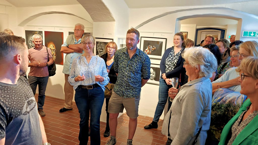 Anke Schön-Erhart und Ronny Claus (M.) sind bei der Ausstellungseröffnung dicht umringt von vielen Besuchern.